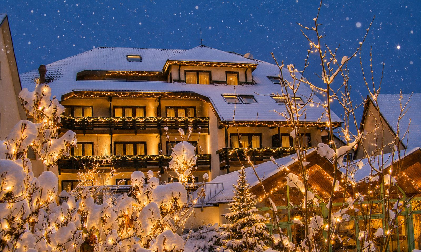 hotel restaurant lamm im schnee bei nacht, mit lichterketten an fassade und wintergarten